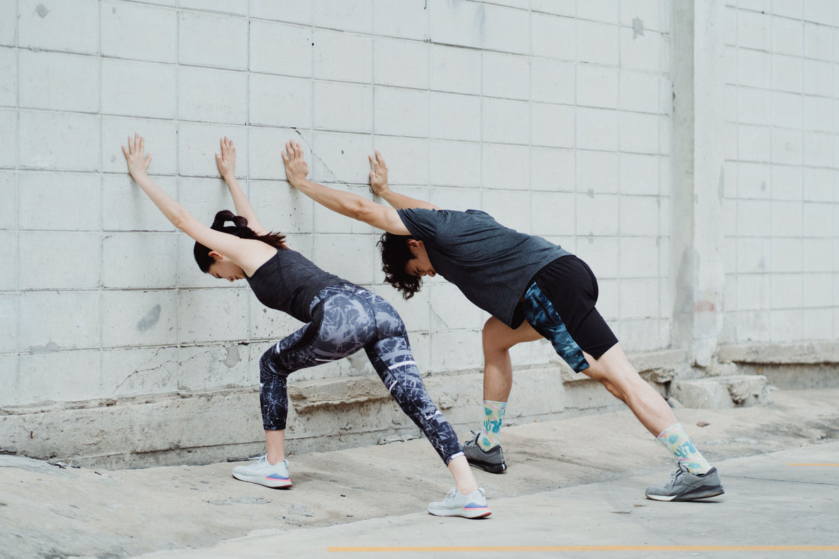 Friends performing wall stretches for effective daily strength training workout.