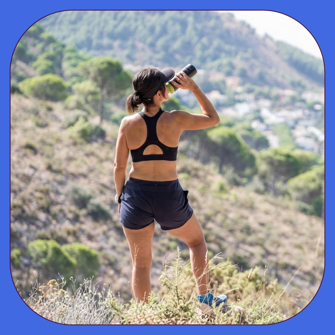 Woman hiking in mountains drinking water from bottle during workout