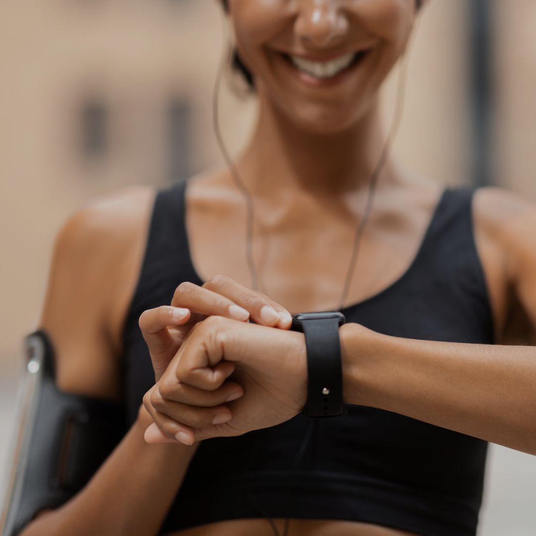 Woman checking fitness smartwatch before starting daily cardio workout outdoors.